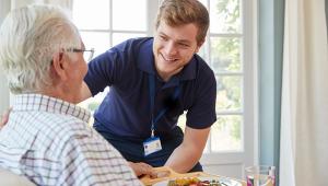 Male care worker serving dinner to elderly man