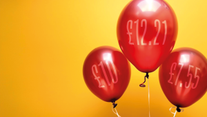 Three shiny red balloons set against a vibrant yellow background.credit_shutterstock_2472941519